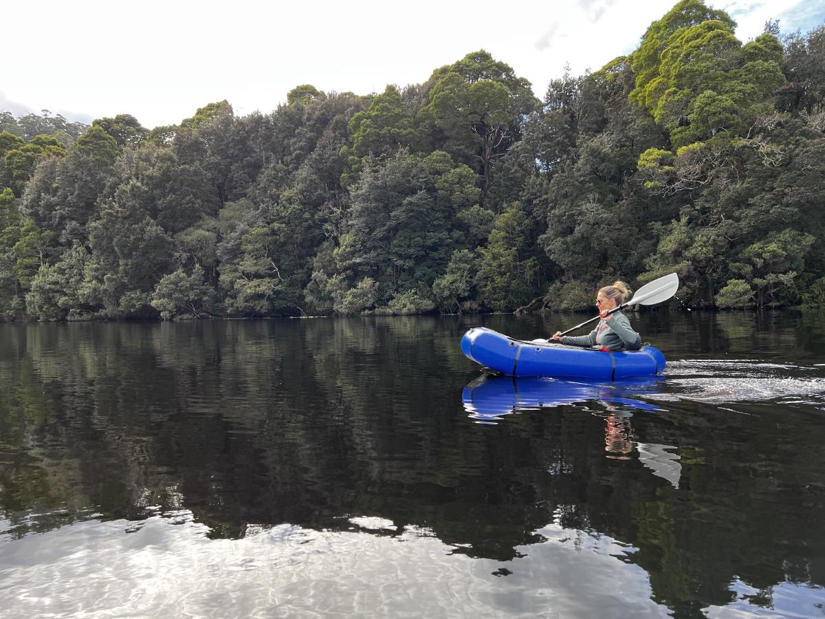 A packraft facing left with trees behind