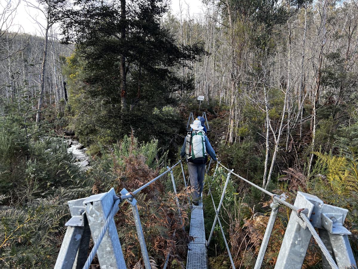 A man crosses a wire bridge