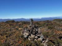 A pile of rocks with a stick shoved into the top of them. The sky is blue.