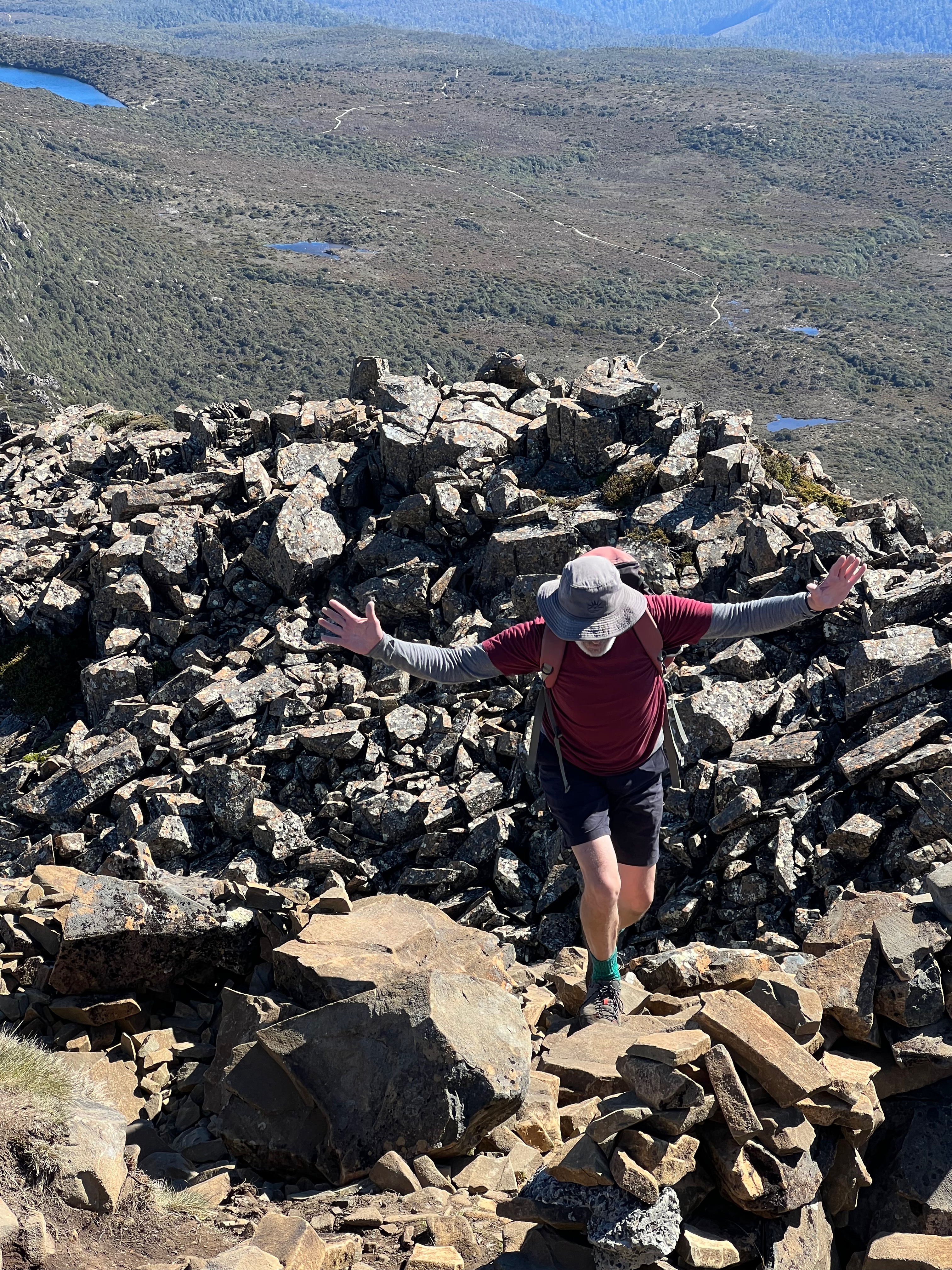 A man nearly at the top of the mountain with his hands out