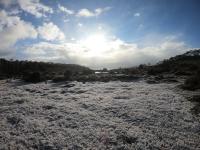 Frost and snow lying on the ground near a lake in the background